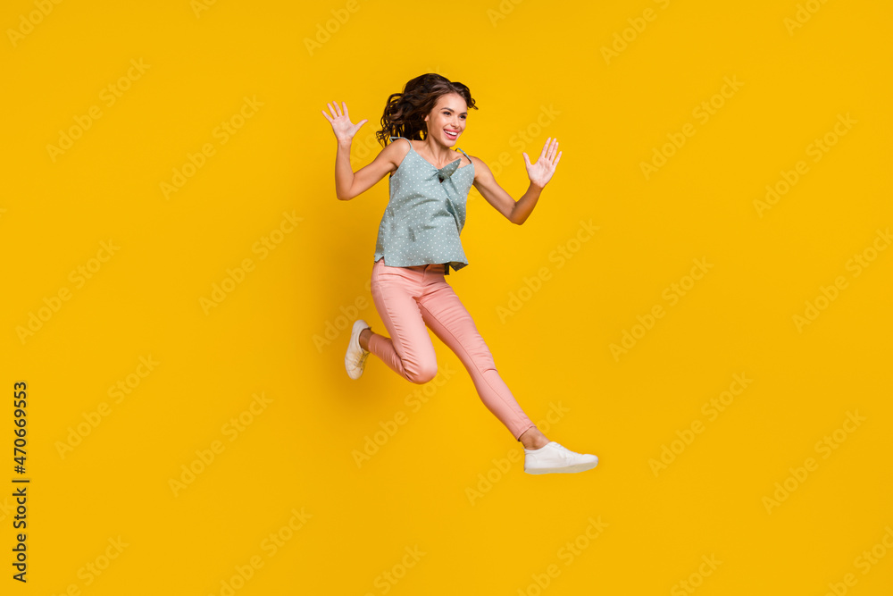 Full body photo of energetic positive woman jump up raise hands enjoy empty space isolated on yellow color background Full body photo of energetic positive woman jump up raise hands enjoy empty space isolated on yellow color background