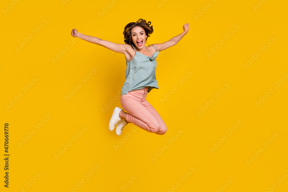 Full length photo of amazed excited happy woman jump up raise hands good mood isolated on yellow color background Full length photo of amazed excited happy woman jump up raise hands good mood isolated on yellow color background