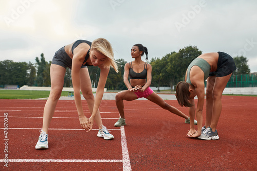 Group of girls stretching on stadium treadmill