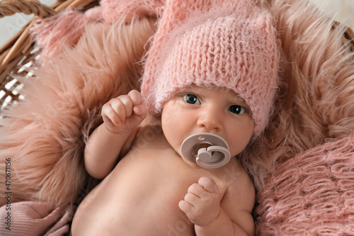 Adorable newborn baby with pacifier in wicker basket, top view photo