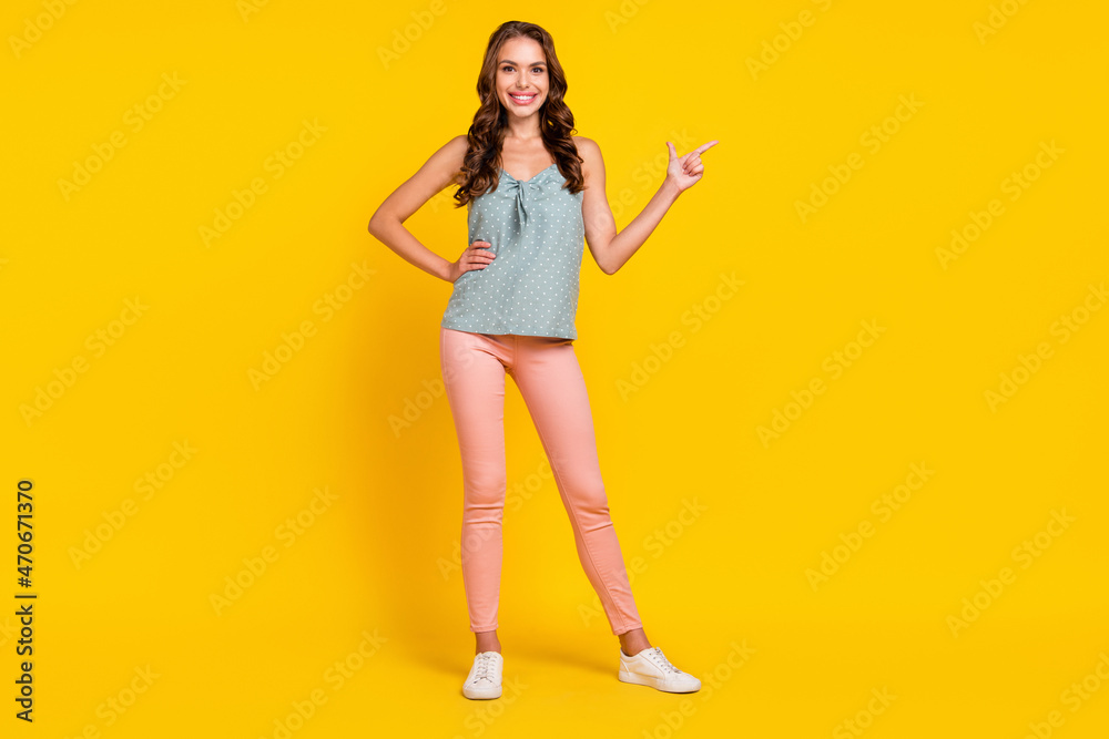 Full length photo of young attractive woman happy positive smile point finger empty space ad choice isolated over yellow color background