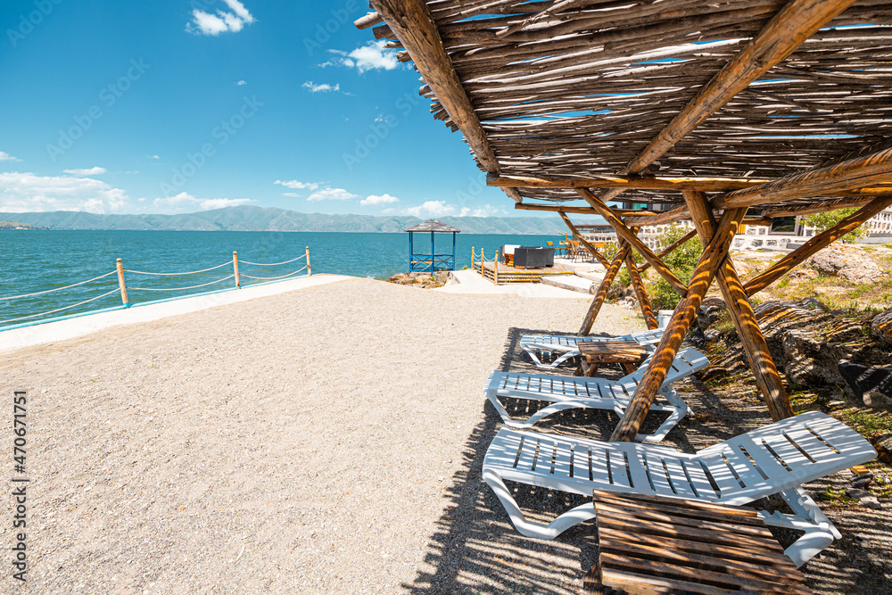 Sun loungers and sunbeds near the sandy beach on Lake Sevan in Armenia. Rest and vacation concept Sun loungers and sunbeds near the sandy beach on Lake Sevan in Armenia. Rest and vacation concept