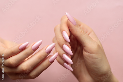 Fototapeta Girl's hands with a beautiful pink manicure on a light pink background