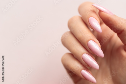 Girl's hand with a beautiful pink manicure on a light pink background