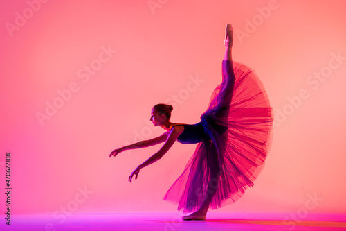 Beautiful young girl ballerina in pointe shoes and a swimsuit silhouette on a bright red background.