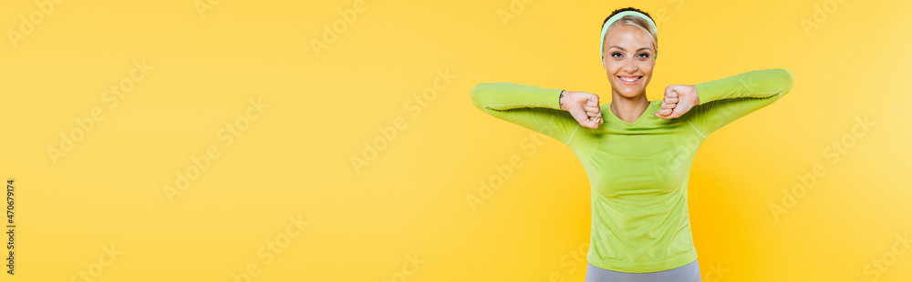 joyful and sportive woman smiling at camera while exercising on yellow, banner joyful and sportive woman smiling at camera while exercising on yellow, banner
