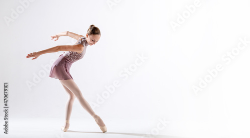 Fototapeta Naklejka Na Ścianę i Meble -  Beautiful young girl ballerina in pointe shoes and pink swimsuit on light background.