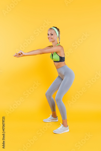 full length view of young and sportive woman doing sit ups on yellow