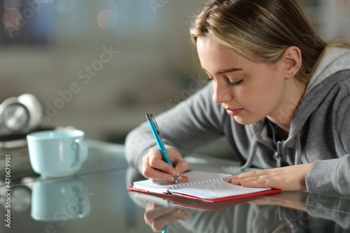 Student writing on agenda in the night at home
