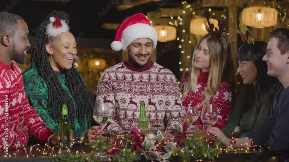 Sliding Shot of Group of Friends Toasting Drinks In Bar During Christmas Celebrations Sliding Shot of Group of Friends Toasting Drinks In Bar During Christmas Celebrations