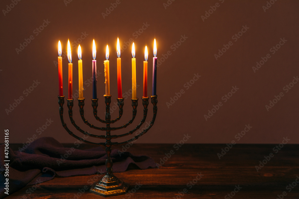 Fototapeta premium Jewish Holiday Hanukkah background with candles and traditional candelabra menorah on dark background. Jew festival of lights concept.