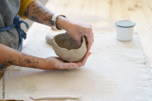 Obraz na plátne Creating handicraft pottery: closeup of working table in ceramics studio with female master shaping wet clay pot
