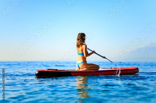 sporty fitness woman on SUP board at sunny nice day on sea © yurakrasil