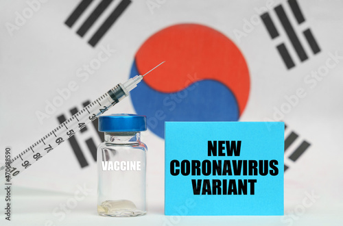 Vaccine, syringe and blue plate with the inscription NEW CORONAVIRUS VARIANT. In the background the flag of South Korea