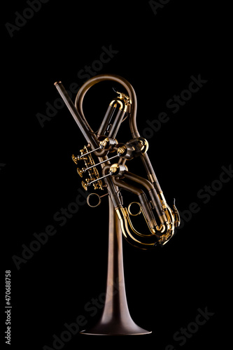 A rotary type trumpet with a curved leadpipe in matte brown with gold elements on a black background photo