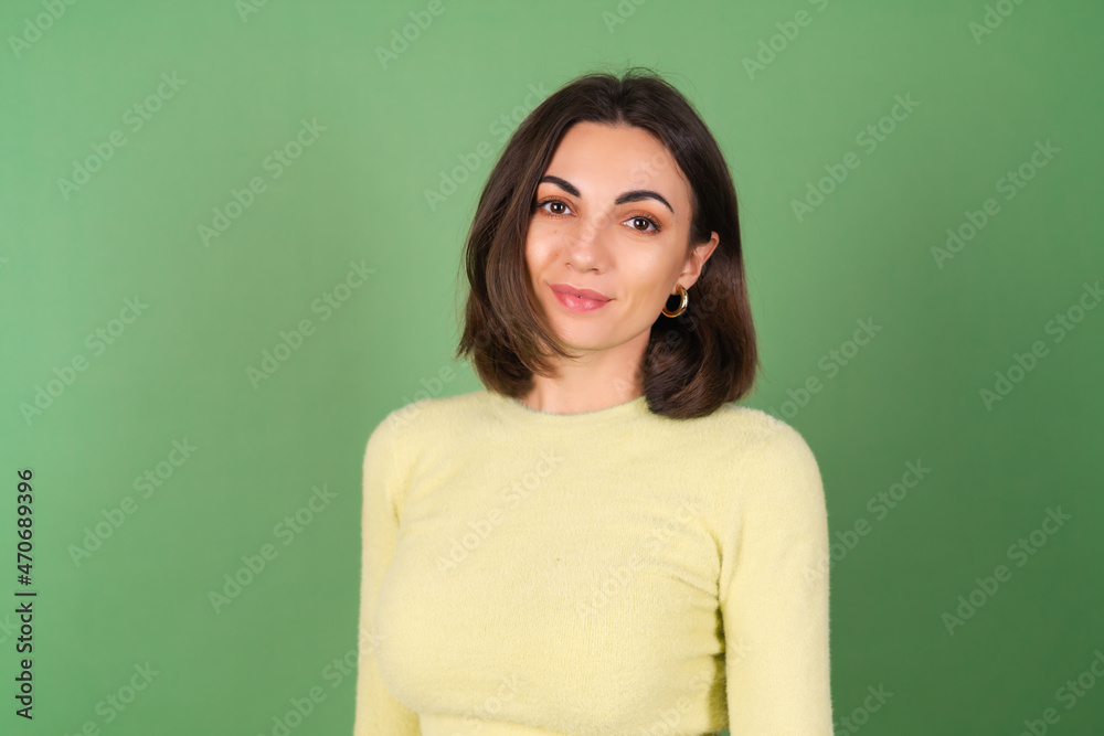 Young woman on a green background in a yellow sweater cute smiling Young woman on a green background in a yellow sweater cute smiling
