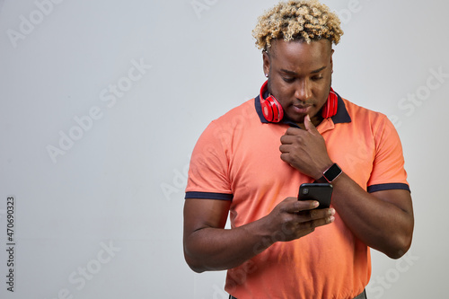 Black man with headphones around his neck was thinking using a smartphone on a white background
