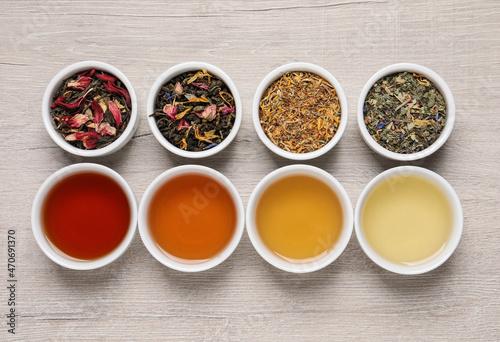 Flat lay composition with different freshly brewed teas and dry leaves on wooden table