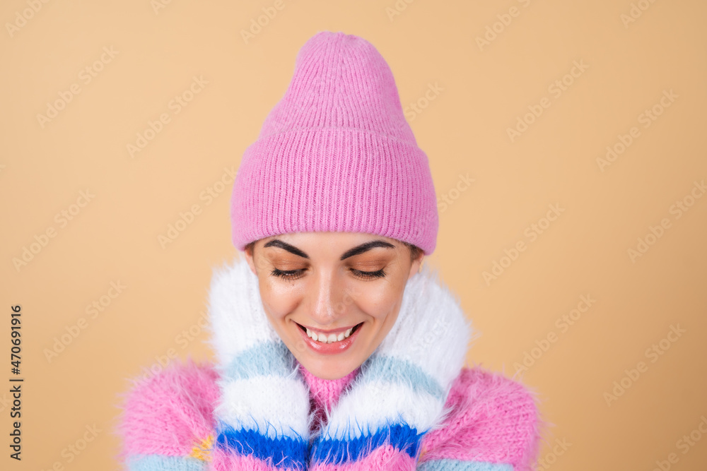 Young woman on a beige background in a bright multi-colored cozy knitted sweater and a hat comfortably hugs herself, warmth and comfort Young woman on a beige background in a bright multi-colored cozy knitted sweater and a hat comfortably hugs herself, warmth and comfort