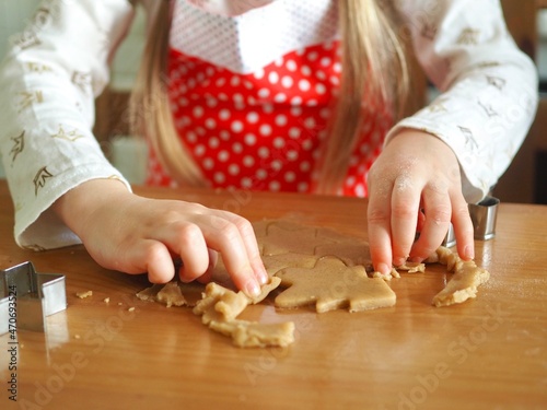 Close-up of children's hands cutting ginger cookies out of dough. Little girl making Christmas cookies. Christmas holidays, moments