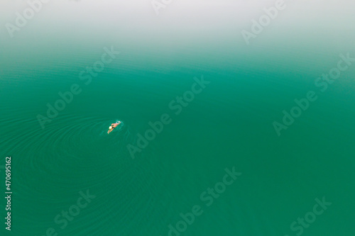 A man swimming in the middle of ocean, lake in diagonal direction towards the center of its turquoise waters
