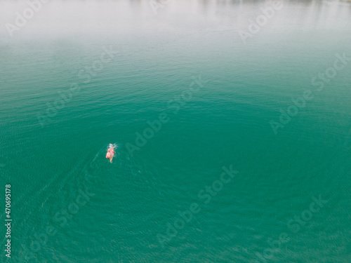 A man swimming freestyle in the middle of ocean, lake in straight direction upwards in turquoise waters © vladimir