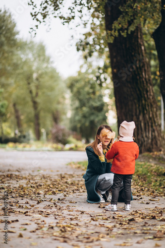 Young mother with her little daughter in an autumn park