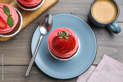 Sweet cupcake with fresh strawberry served on wooden table, flat lay