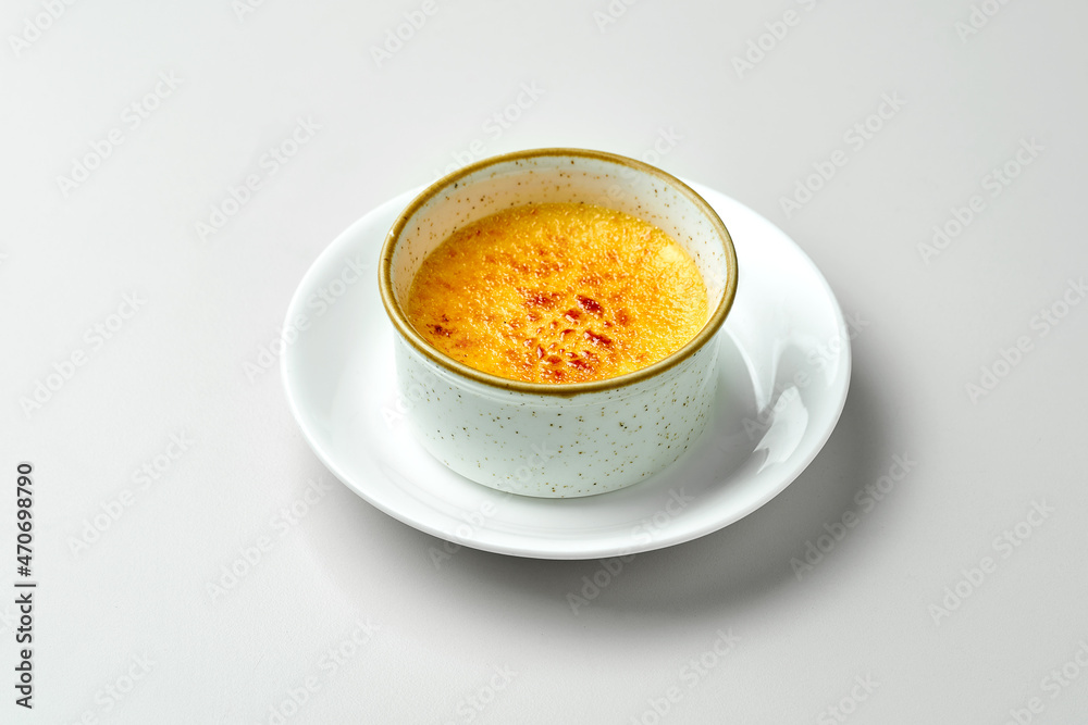 Dessert creme brulee in a white plate on a gray background. Dessert creme brulee in a white plate on a gray background.