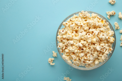 Popcorn in glass bowl on blue background.