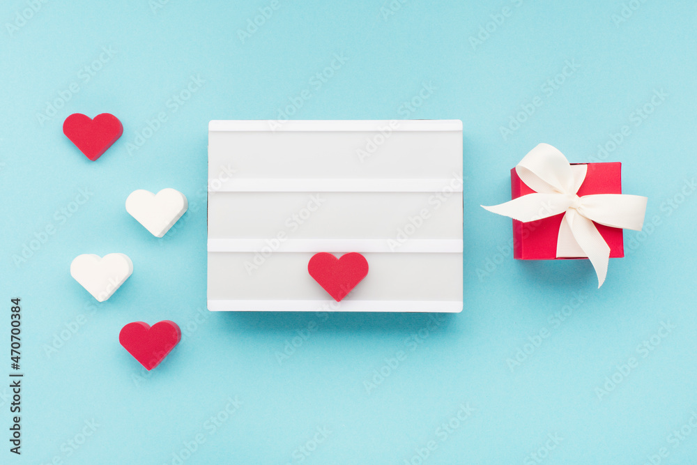 Red gift box, heart and empty white lightbox on blue background. Valentines day concept. Red gift box, heart and empty white lightbox on blue background. Valentines day concept.