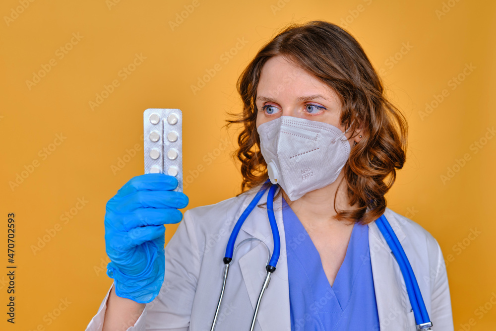 A female doctor holds a package of pills, studio background
