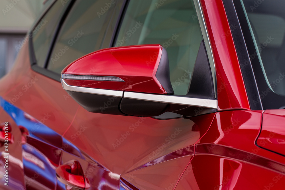 Close up front view of car side mirror. Front rear view mirror on the car window. Car exterior details. Red car mirror.