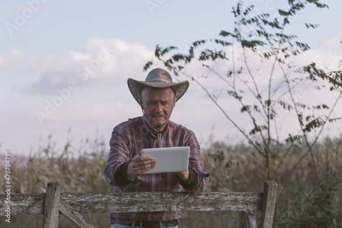 Farmer using digital tablet at agricultural field to buy online some staff