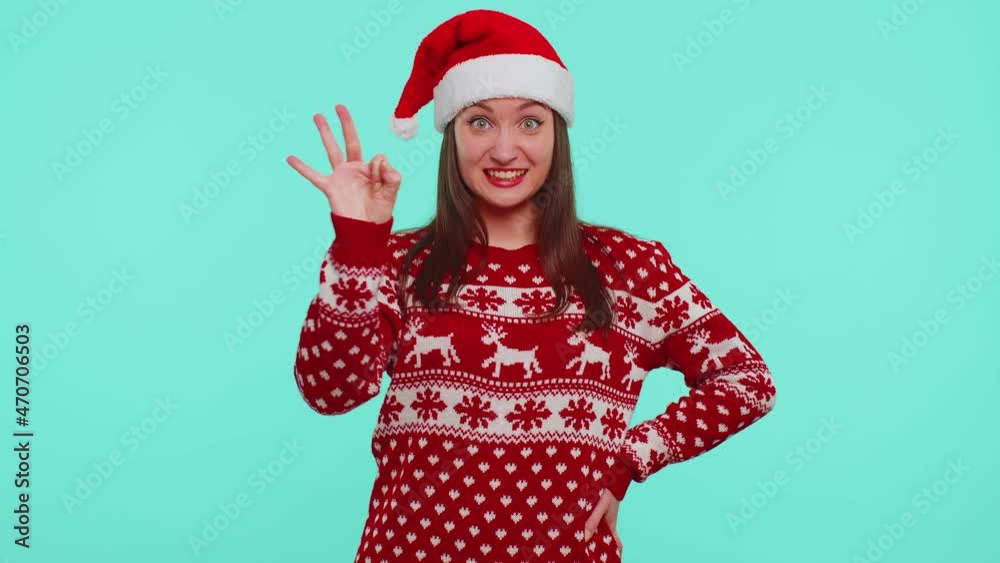 Countdown to holiday celebration. Cheerful girl 20s in red Christmas Santa sweater hat counting in reverse order from five to one on blue studio background. Win scream, winner gesture. Happy New Year Countdown to holiday celebration. Cheerful girl 20s in red Christmas Santa sweater hat counting in reverse order from five to one on blue studio background. Win scream, winner gesture. Happy New Year