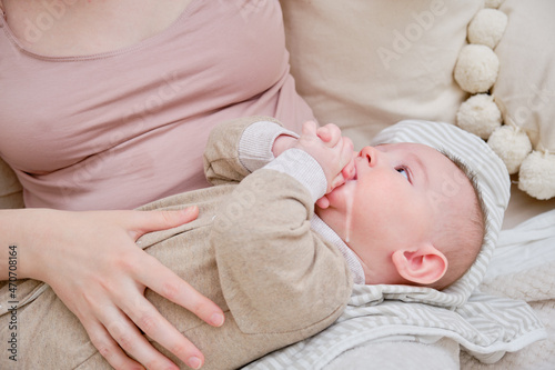 A mother woman holds an infant baby to regurgitate excess air after breastfeeding. Mom with a child boy after feeding