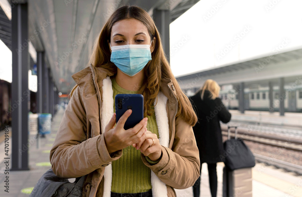 Fototapeta premium People with surgical mask using smartphone at train station