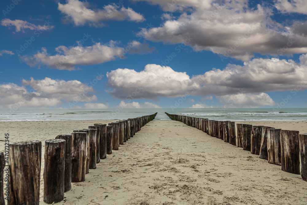 Sandy beach at Burgh-Haamstede in the Dutch province of Zeeland with a double row of posts of beach in the sea intended as functional coastal protection with veil clouds and cumulus clouds Sandy beach at Burgh-Haamstede in the Dutch province of Zeeland with a double row of posts of beach in the sea intended as functional coastal protection with veil clouds and cumulus clouds