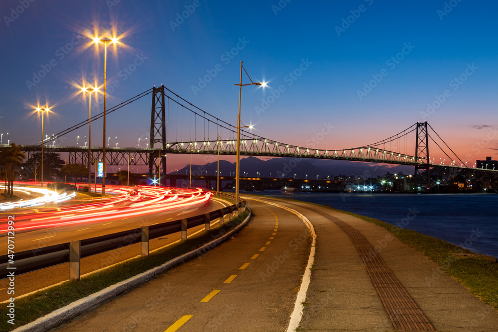 Anoitecer em Florianópolis vista da avenida Beira-Mar Norte com as luzes do trafego de carros e o calçadão ao fundo a Ponte Hercílio Luz , Florianopolis, Santa Catarina, Brasil  