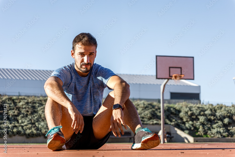 caucasian basket player sat on the court, looking at camera with serious expression
