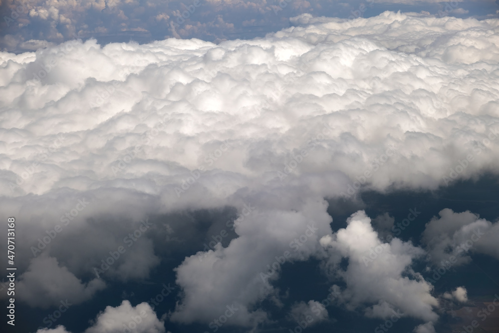 Fototapeta premium Aerial view from airplane window of white puffy clouds on bright sunny day.