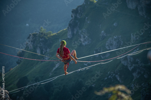 Camminare in equilibrio sulla corda slackline a grandi altezze tra le montagne photo