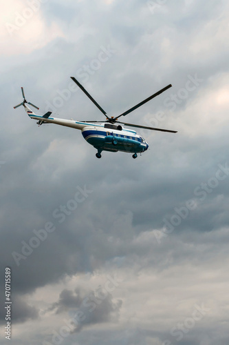 Passenger helicopter Mi-8 flies in the gray cloudy sky