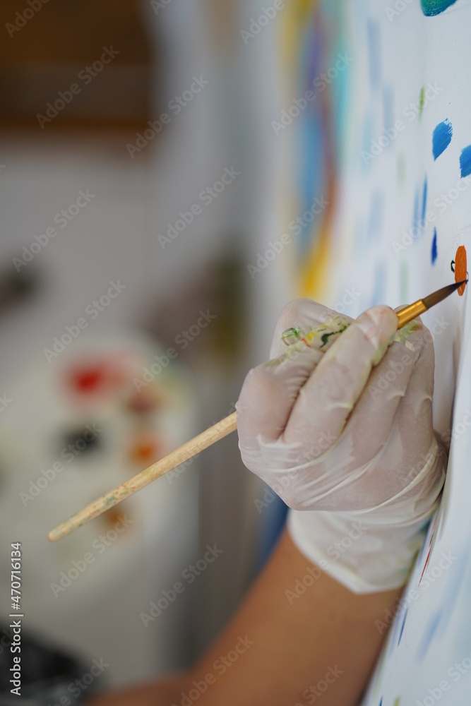 Hand in a rubber glove painting a picture with paints on canvas foto de