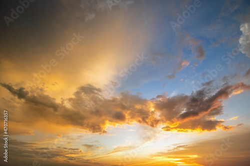 Dramatic sky at sunset with puffy clouds lit by orange setting sun. © bilanol