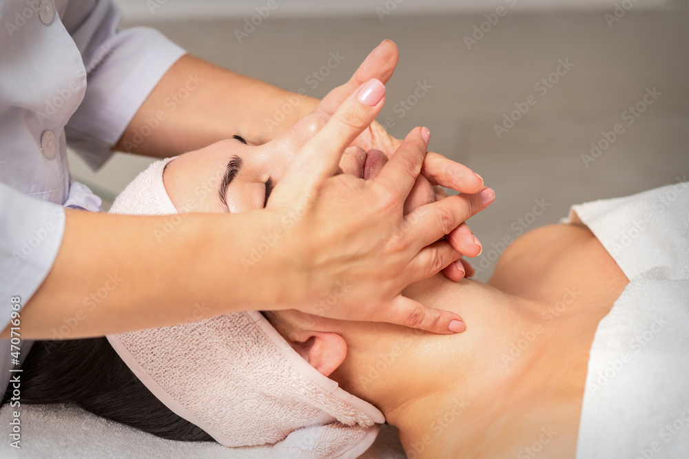 Beautiful caucasian young woman getting a facial massage at a beauty salon.