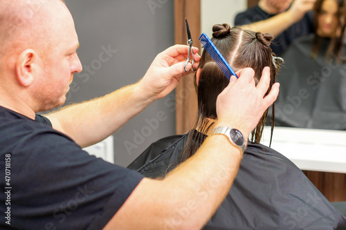 Male stylist cutting the hair of female client in professional beauty salon.