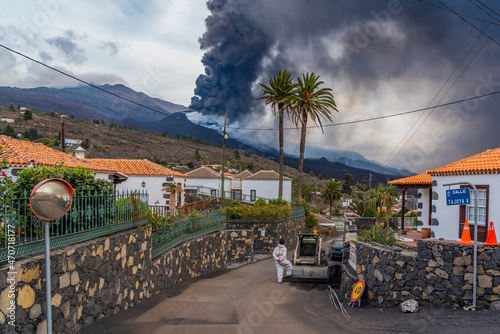 LOS LLANOS DE ARIANE, SPAIN NOVEMBER 10.2021: Man looking to the Cumbre Vieja volcano eruption after cleaning the street from ash at the Canary island of La Palma, photo