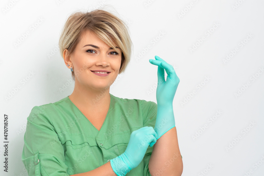 Doctor beautician puts on sterile blue gloves smiling prepares to receive clients on white. Doctor beautician puts on sterile blue gloves smiling prepares to receive clients on white.