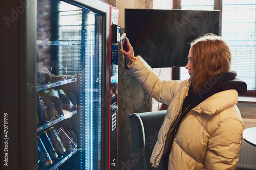 Woman paying for product at vending machine using contactless method of payment with mobile phone. Woman using new way of payments © Przemek Klos